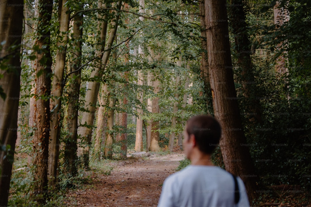 Person walking outdoors on a green path in daylight with a relaxed pace.