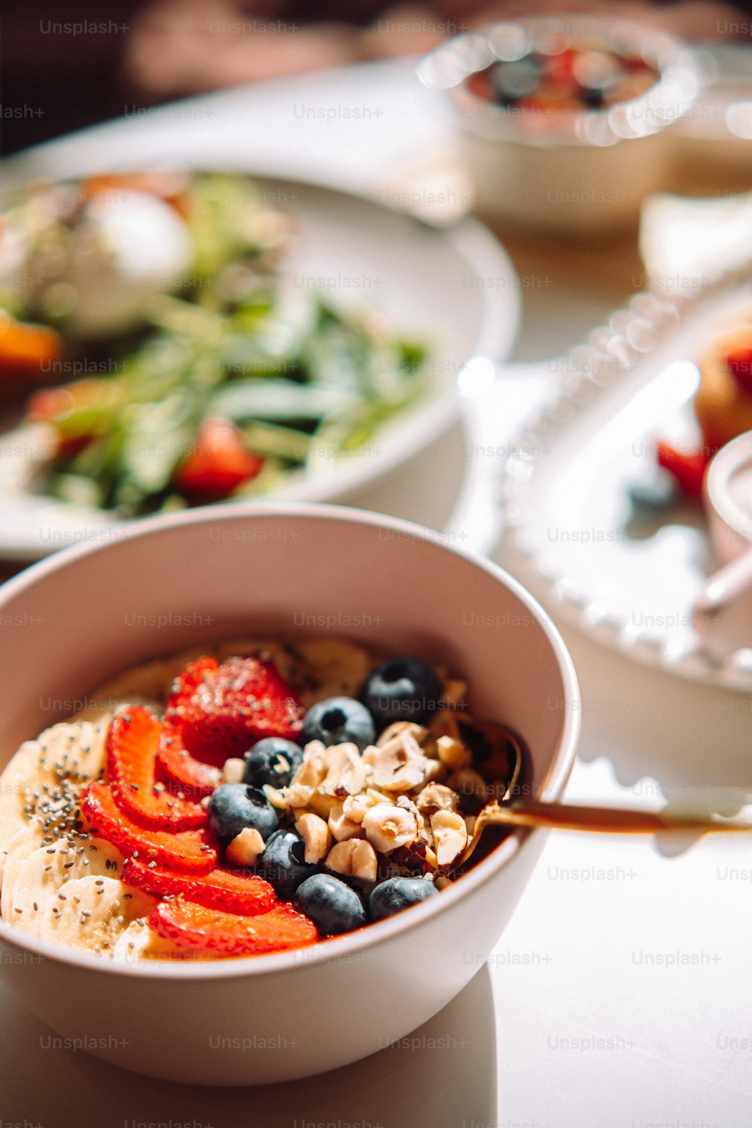 Bowl of oats and seeds with a spoon beside a glass of water on a kitchen counter.